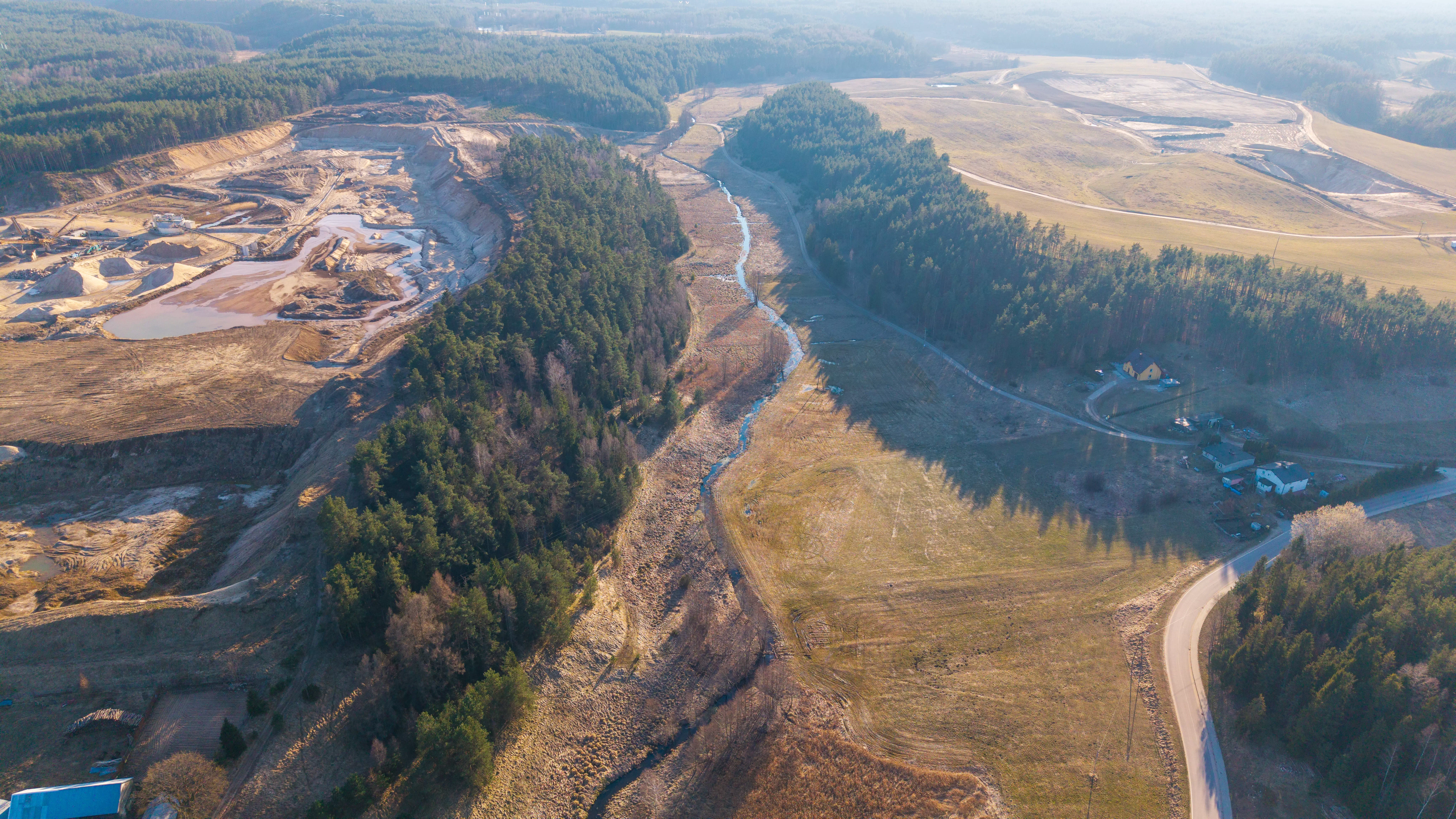 Szeroki widok na miasto położone nad jeziorem, otoczone polami i lasami, zdjęcie z powietrza