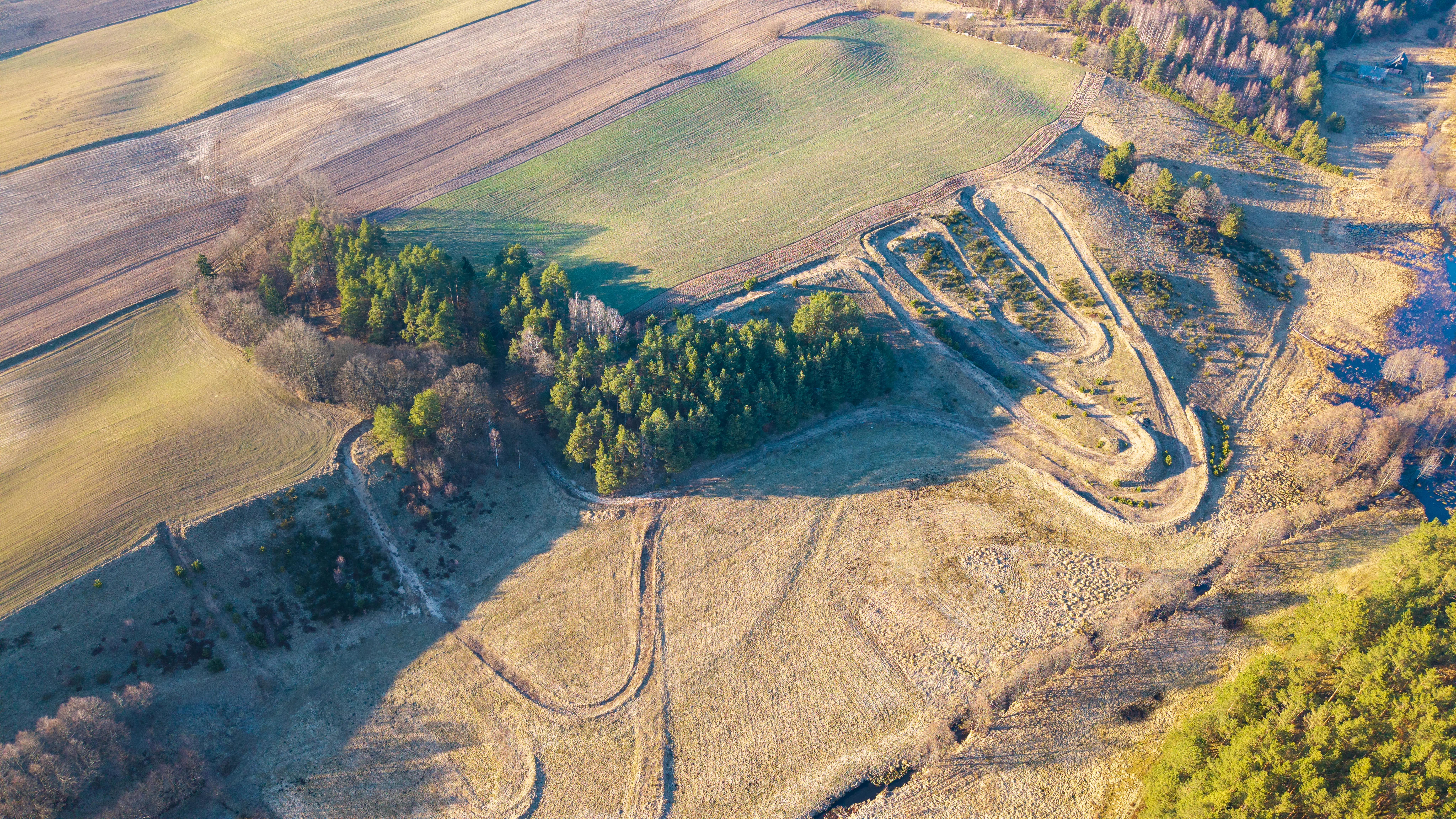 Jezioro otoczone polami uprawnymi, lasami i zabudową wiejską, widok z lotu ptaka