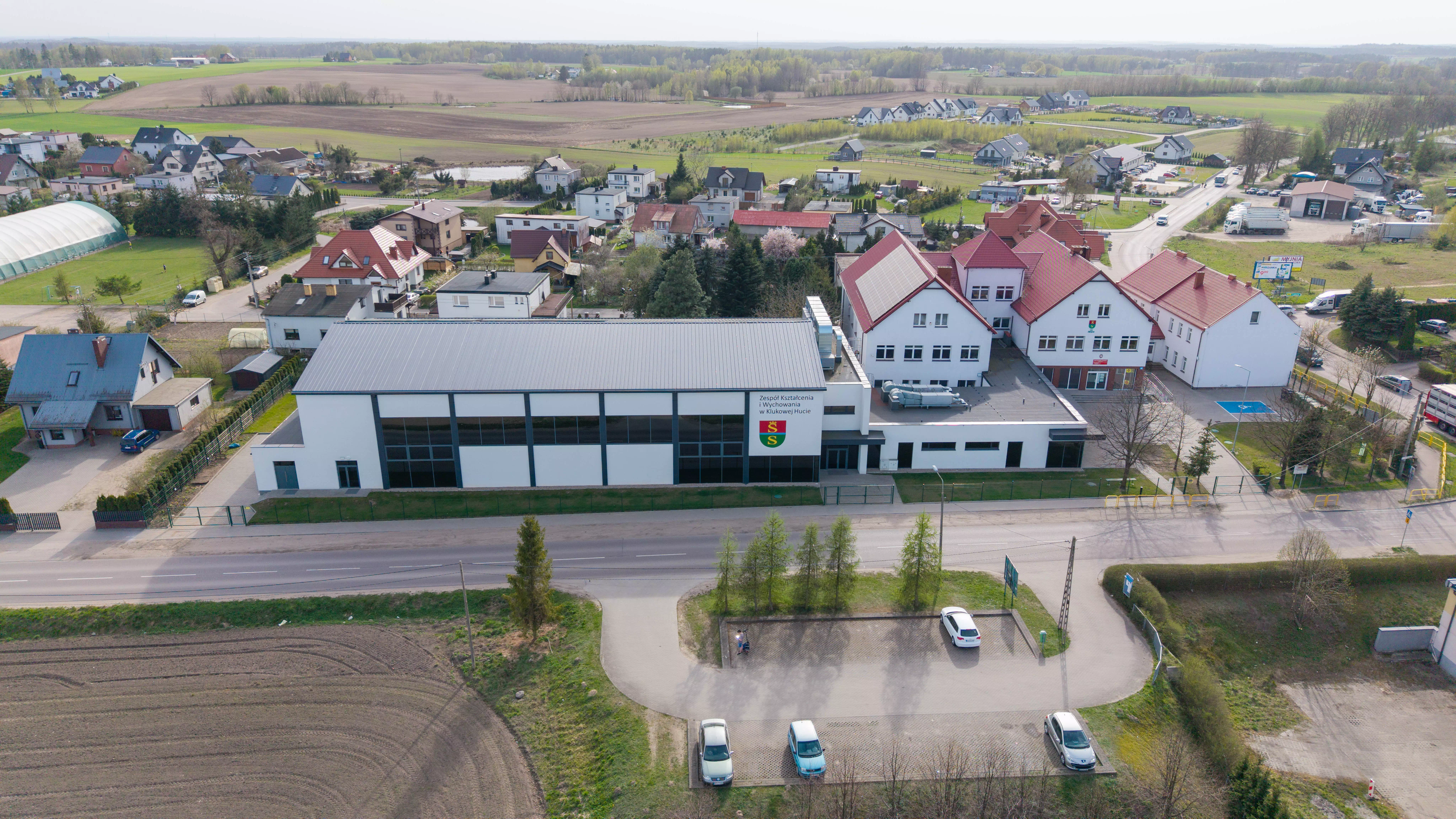 Zespół szkolno-przedszkolny i hala sportowa w otoczeniu domów jednorodzinnych, widok z lotu ptaka
